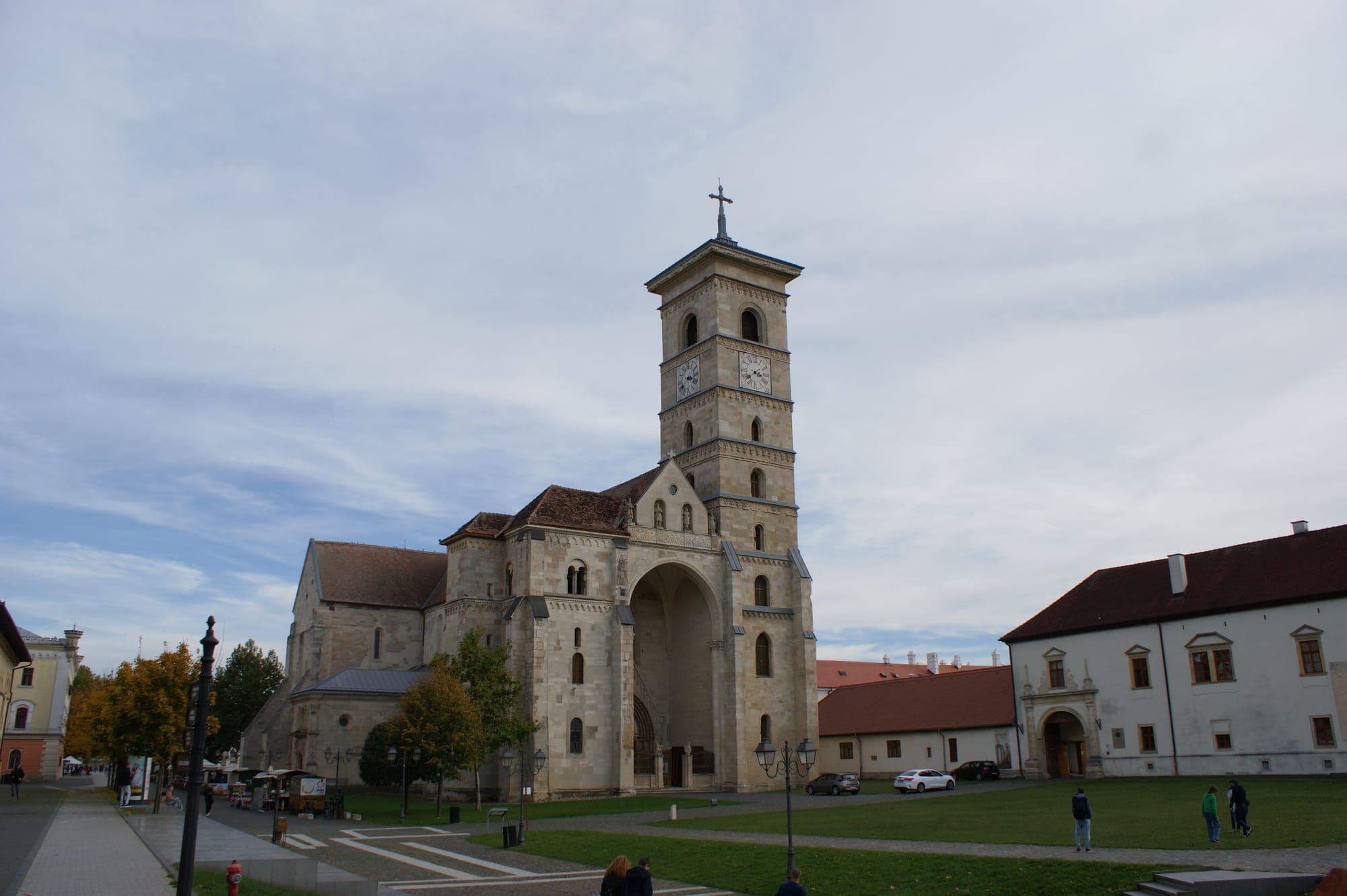 Fațada de vest a catedralei, cu pronaosul boltit și turnul sudic cu ceas, văzută din piața cu gazon, toamna